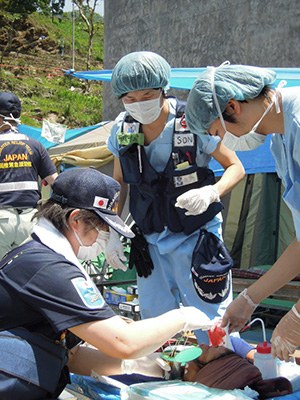 余震で負傷した被災者を、野外で処置する赤沢師長（写真提供：JICA）