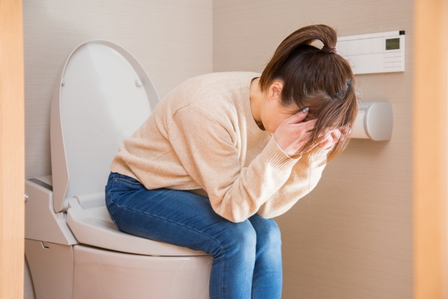 トイレで悩む女性のイメージ写真