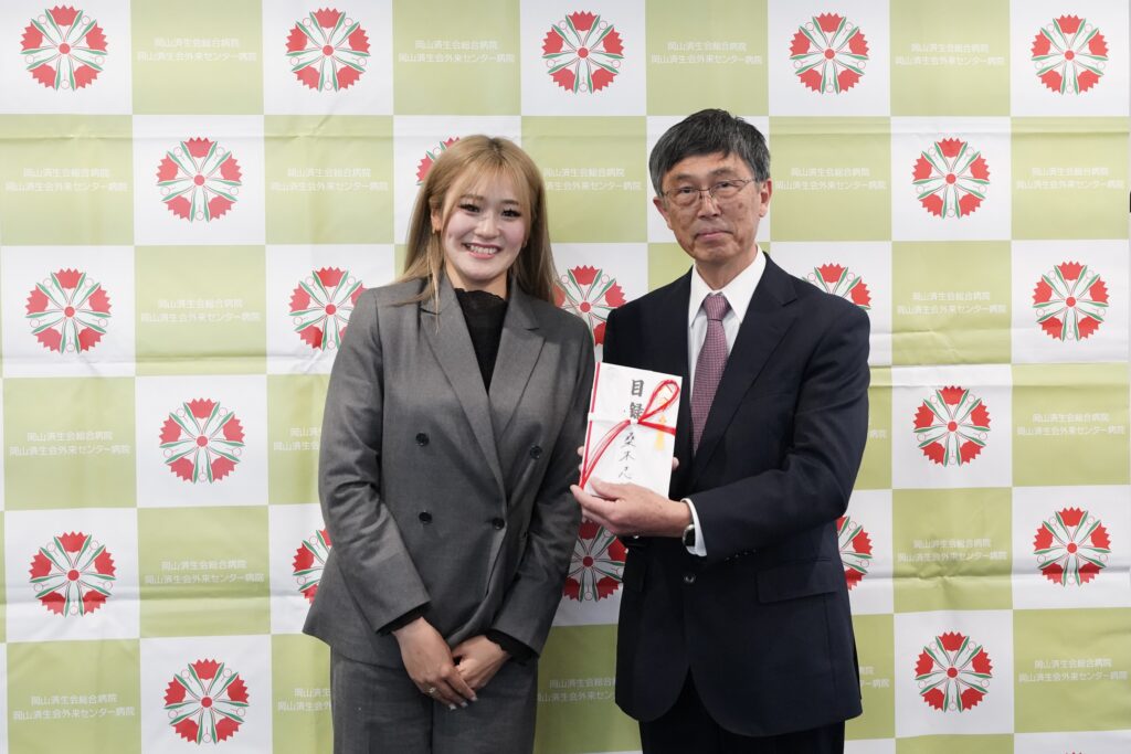 いただいた寄附目録を持ち記念撮影する仁熊健文院長と桑木志帆選手